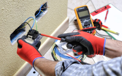 Electrician technician at work blocks the cable between the clamps of a socket in a residential electrical installation